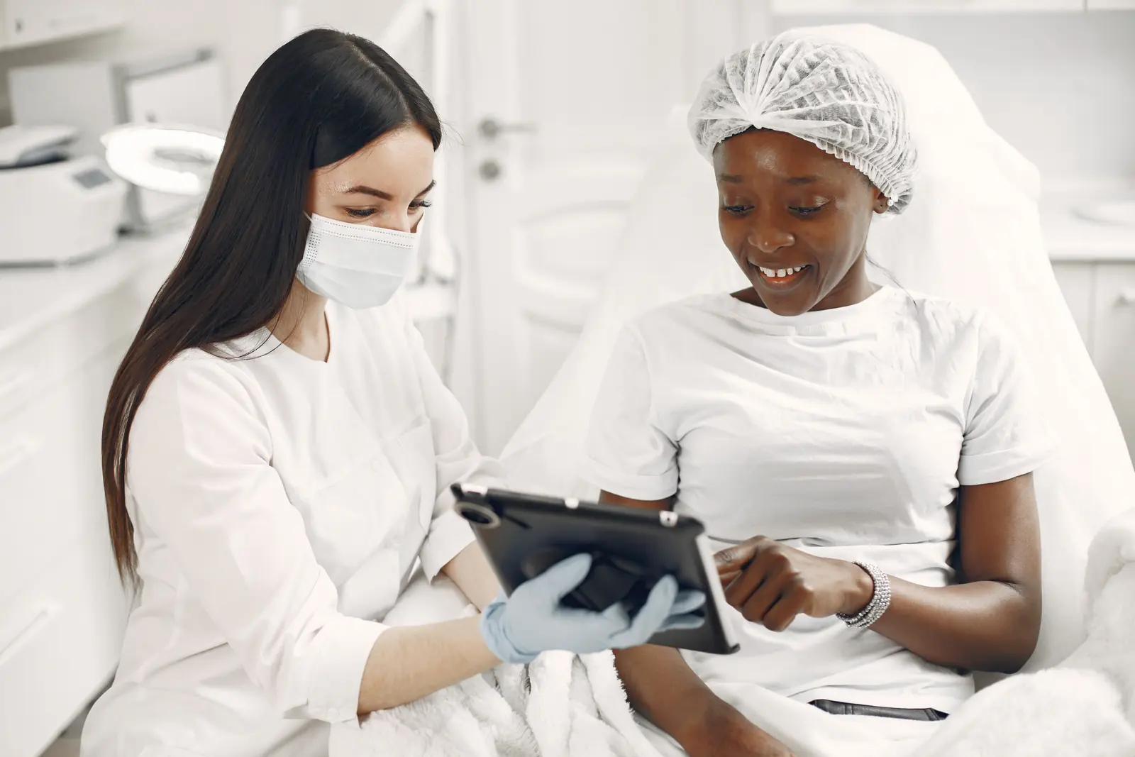 A clinician examining an adult patient's skin with a handheld diagnostic device.