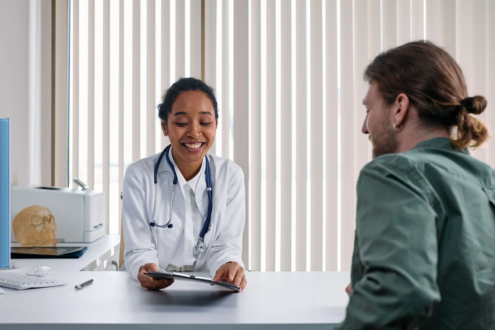 A clinician and a patient discussing care together at a desk.