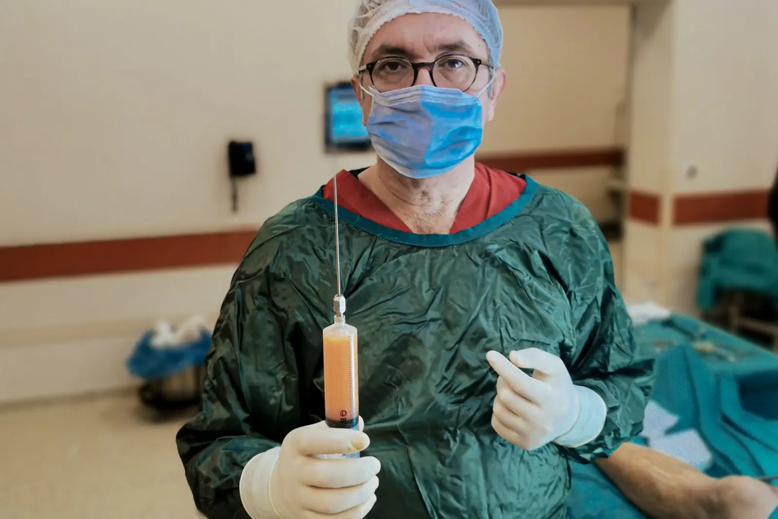 A surgeon holding a medical instrument used during liposuction in a clinical setting.