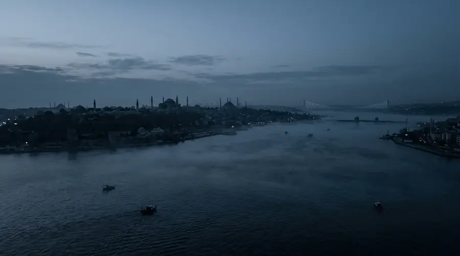 Istanbul before dawn, seen across the Bosphorus: domes, minarets and a bridge on a quiet horizon.