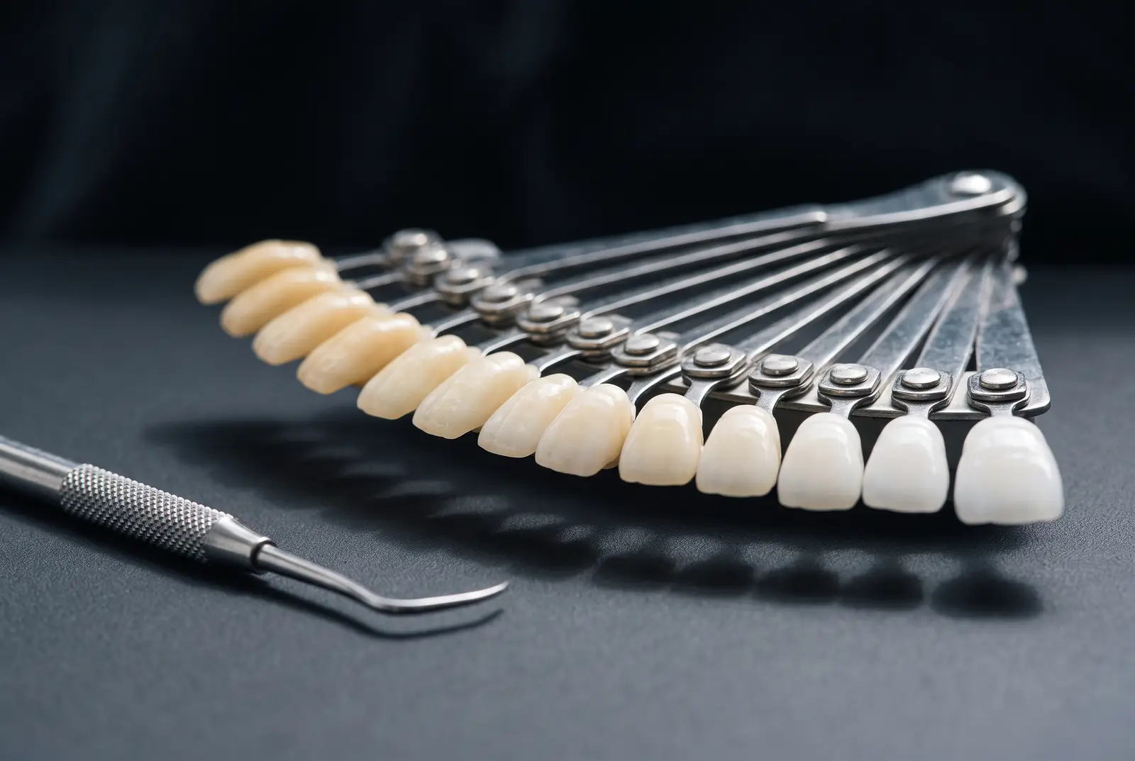 A dental shade guide fanned open, its tabs graduating from deeper ivory to bright white.